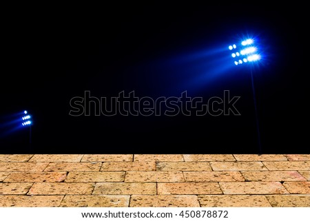Stadium floodlights on a sports field at night with brick wall