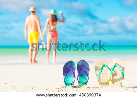 picture of two flip flops with young couple on beach backgroung