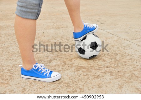 Cropped image of a man foot on a soccer ball in the street 