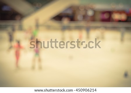 Blurred abstract motion background of parents and kids play indoor ice skating in modern shopping mall. Defocused of indoor ice skating with people on ice rink. Natural light from glass roof. Vintage.