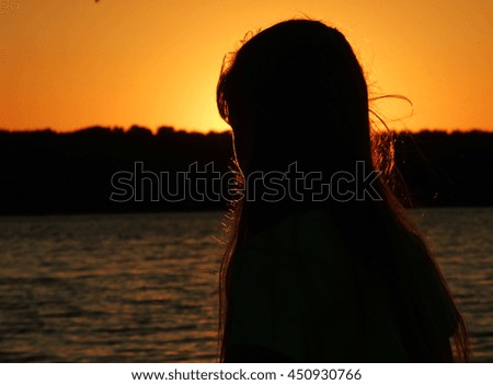 Silhouette of girl at sunset. Coast.