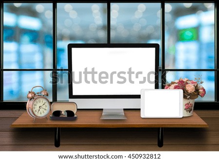 Top wooden shelves with computer, taplet, alarm clock and glasses on the wooden wall with store blurred background.Product presentation concept