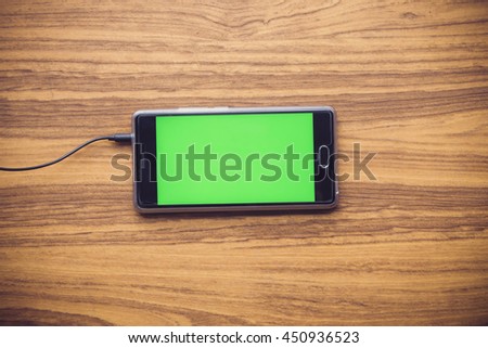 Smart phone with green screen on wooden table background