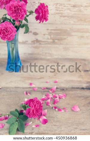 Still life with pink roses flower in blue vase on grunge wooden background,retro effect
