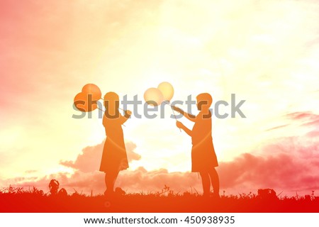 Silhouette children with balloon at sunset