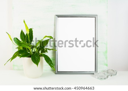 Silver frame mockup with flower pot and candles. Portrait or poster white frame mockup. Empty white frame mockup for presentation artwork design.