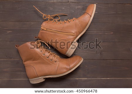 Traditional leather cowboy boots are on the wooden background.