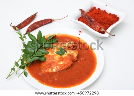 Red spicy hot Kerala fish curry and green curry leaf, India. South Indian sea food with pearl spot/ tilapia. Popular in coastal area of Sri Lanka. with green chili, coconut milk, mango Asian cuisine.