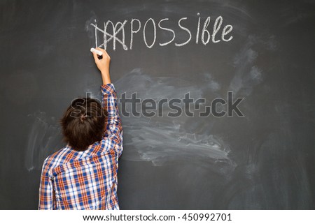 boy putting a cross over impossible on blackboard
