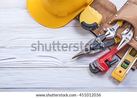 Set of construction tooling in tool belt hard hat on wooden board. Royalty-Free Stock Photo #451012036