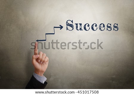 Businessman hand point at sketching arrow in direction to text Success, business concept of reaching success. Glow light effect, vignette and shadow on concrete wall background. 