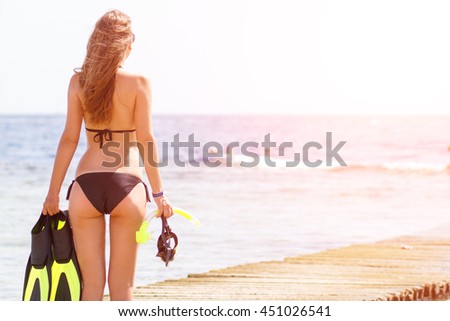 Young slim woman with snorkeling equipment standing near sea. Caucasian girl with flippers, mask and snorkel. Scuba diving or snorkel background
