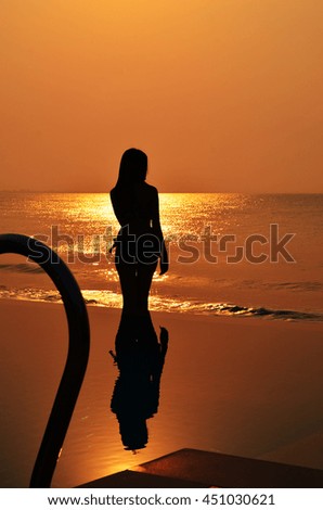 Woman in swiming suit on beach at silhouette time,Back view