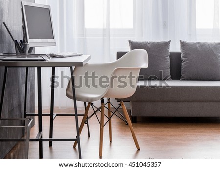 Modern, bright living room arranged in grey, with computer desk and chair