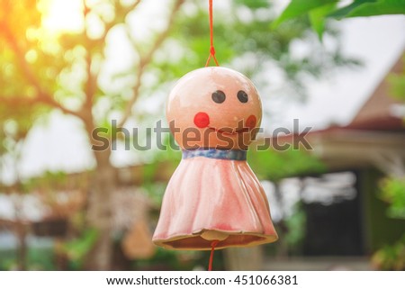 Mobilr ceramic doll hanging in blur nature background