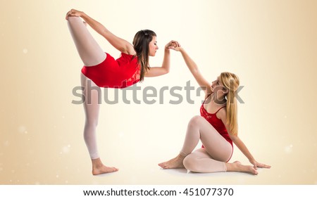 Two girls dancing ballet over ocher background