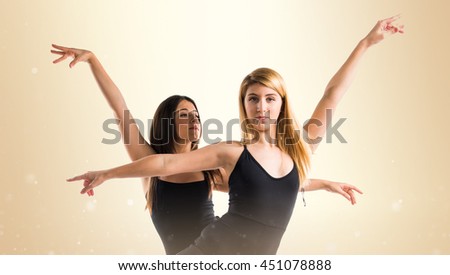 Two girls dancing ballet over ocher background