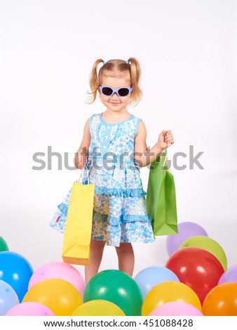 Shopping child. little girl holding shopping bags.Multi-colored balloons. Isolated on white background