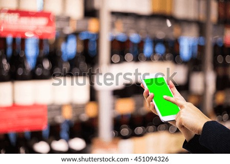 Girl touching Cell phone with green screen in shopping mall