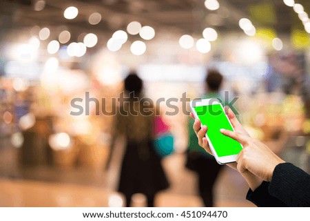 Girl touching Cell phone with green screen in shopping mall