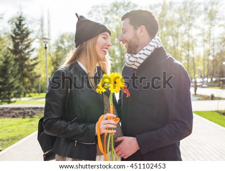 Smiling man embracing happy pregnant woman in a park