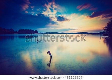 Vintage photo of sunset over calm lake in Poland. Old photo of lake sunset.