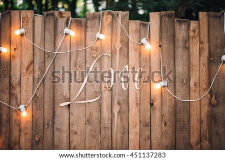Wedding. Wooden wall decorated by electric lamps and Love sign. Reception. Lounge zone.