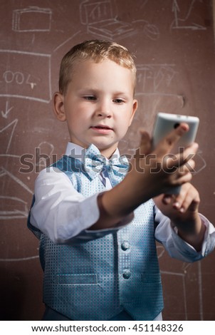Little schoolboy makes a selfie, boy in suit on the background of the school Board, the young blonde with the phone