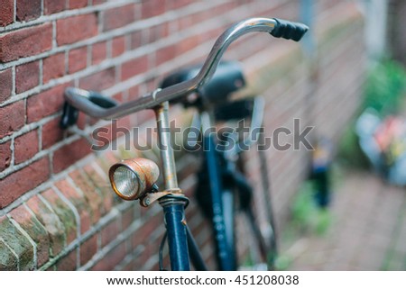 Old vintage bicycle parked in near the brick wall. Detail close up. Bokeh background. Soft shallow focus. Travel inspiration. Postcard concept. 
