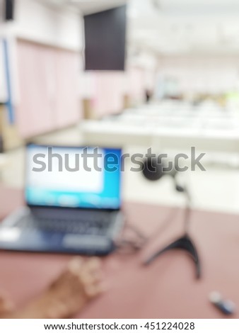 Blurred abstract background of meeting room with computer notebook and microphone from speaker view. Defocus laptop in classroom with projector. Blurry image of monitor in conference seminar business.