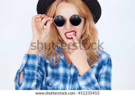 bright closeup portrait picture of funny teenage girl in shades. Fashion carefree hipster young woman with blond hair biting finger