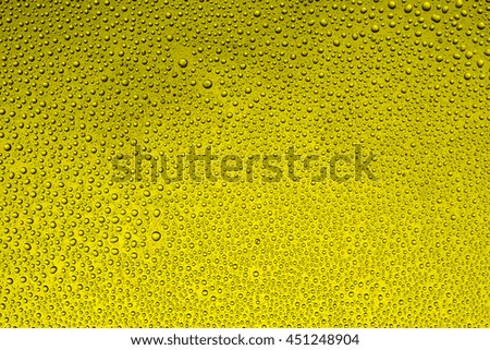 Drops of water on glass on a yellow background, small