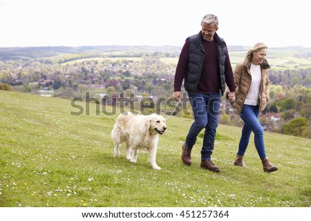 Mature Couple Taking Golden Retriever For Walk Royalty-Free Stock Photo #451257364