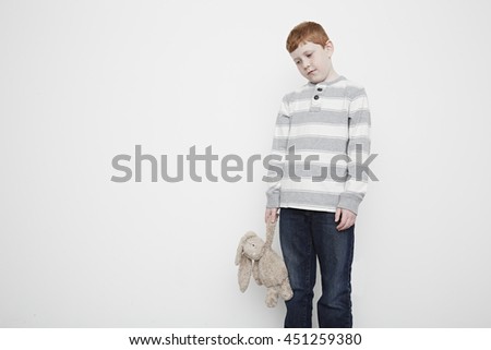 Boy looking downcast holding teddy bear
