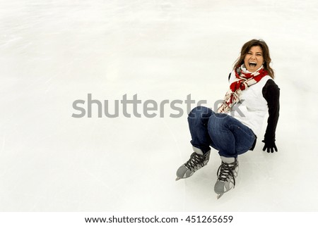 Young woman wearing ice skates, falling down laughing