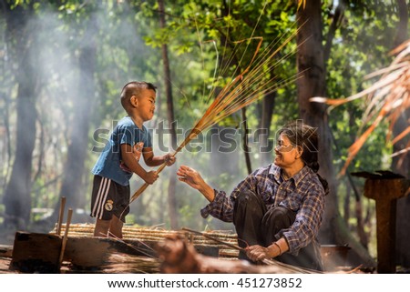 Grandmother and her grandson were fabricated leaf roof. Show their smile , that mean's the good relation between them. This is beautiful life in side-country of south east Asia. Royalty-Free Stock Photo #451273852
