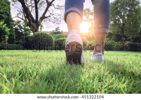 Woman jeans and sneaker shoes on Sunset walking in garden Royalty-Free Stock Photo #451322104