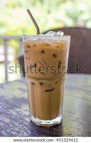 vertical picture of glass of ice espresso on wooden table in coffee bar