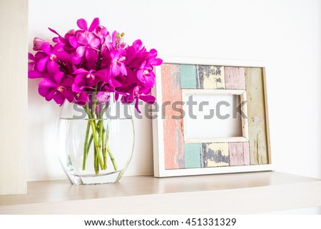 Old wooden photo frame with orchid flower in vase decoration interior of room