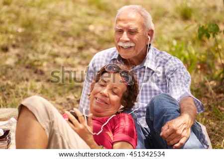 Old people, senior couple, elderly man and woman in park. Grandpa and grandma listening to song, music with mp3 player Royalty-Free Stock Photo #451342534