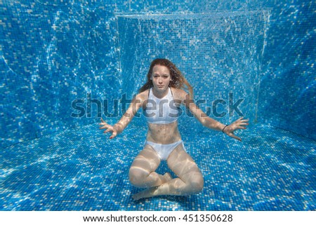girl in the pool. She dives into the pool. Under water in a white bathing suit