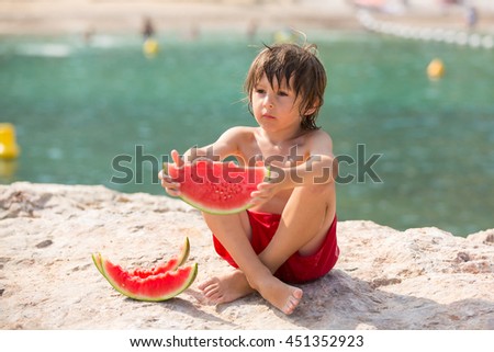 Cute little child, boy, eating watermelon on the beach, summertime