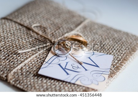 wedding rings resting on a hessian covered wedding invitation