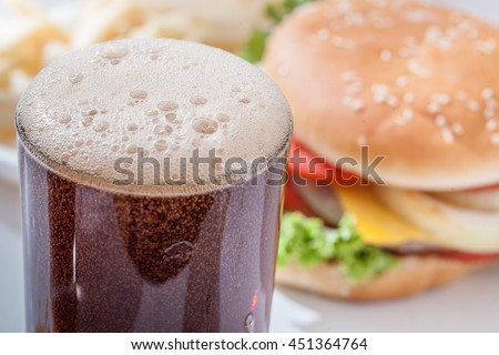 Soft drink pouring in a glass with hamburger on  white background
