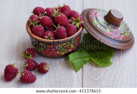 Ripe sweet raspberries in bowl on wooden table. Flat lay.
