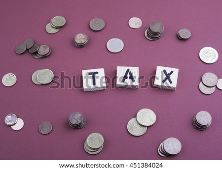 Text: TAX from wooden letters on a red office desk