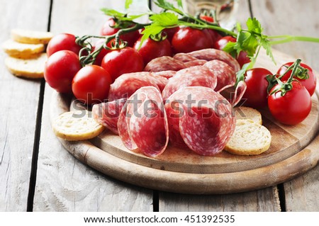 Fresh salami with tomato and bread, selective focus