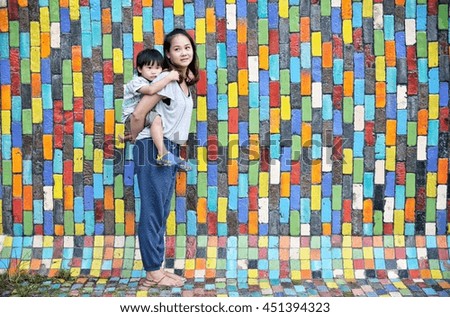 Mother and son in piggyback on colourful background