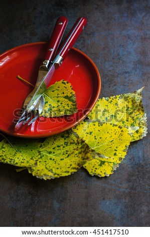 Autumnal table setting with vintage table silverware and yellow leaves