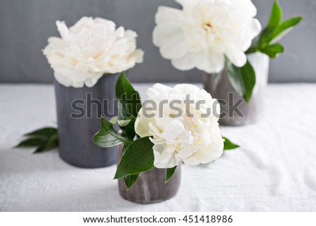White peonies in gray handmade ceramic cups